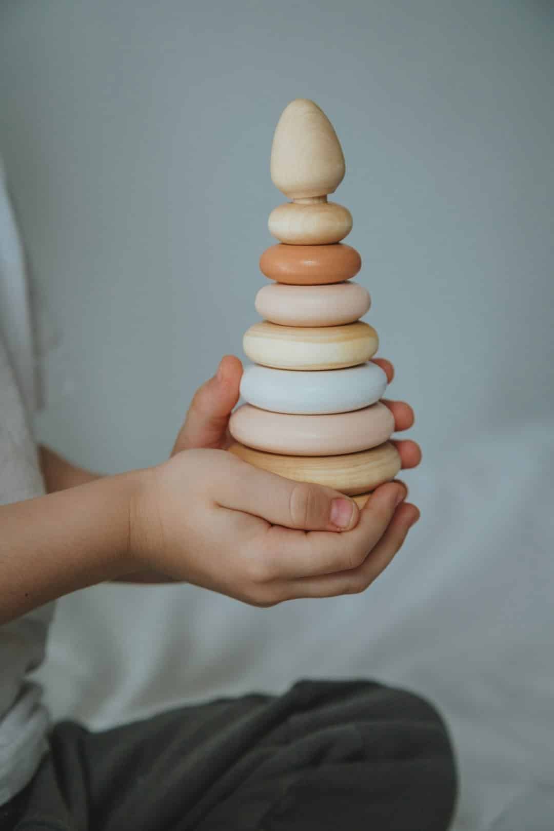 Child plays with colorful building blocks on a brown cushion.